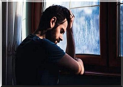 Man stands sad by the window