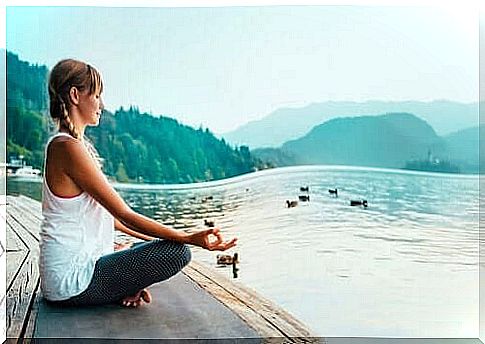 A woman meditates by a lake
