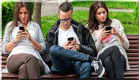 Group of people on a bench looking at their phones